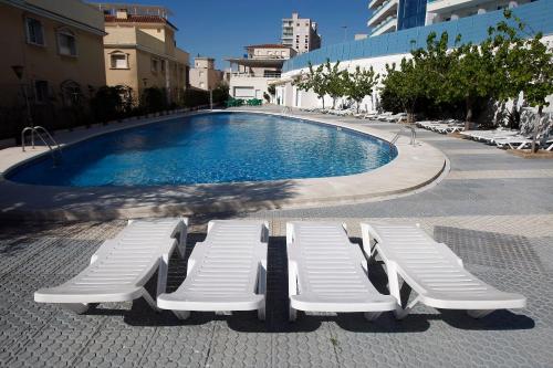 two lounge chairs and a swimming pool in a city at Hotel Natura Park in Comarruga
