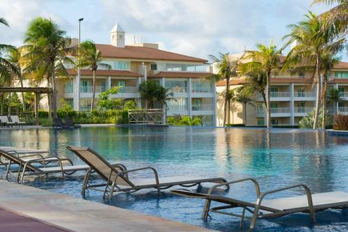 einen Pool mit Liegestühlen vor einem Hotel in der Unterkunft Golf Ville Residence Resort, apartamento 3 suítes, 110m2, Porto das Dunas próx ao Beach Park in Aquiraz