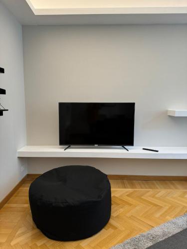 a black ottoman sitting in front of a tv at Casa nel Vicolo - Duomo di Osimo e 20 min da Loreto in Osimo