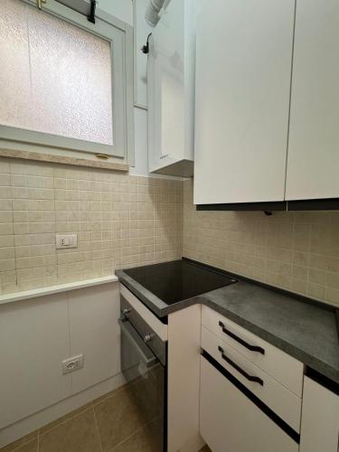 a kitchen with white cabinets and a black counter top at Casa nel Vicolo - Duomo di Osimo e 20 min da Loreto in Osimo