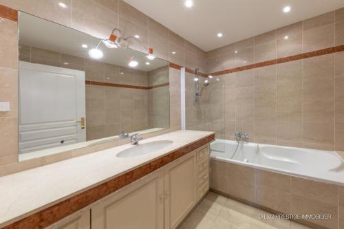 une salle de bain avec un lavabo, une baignoire et un miroir dans l'établissement Theoule Beach, à Théoule-sur-Mer