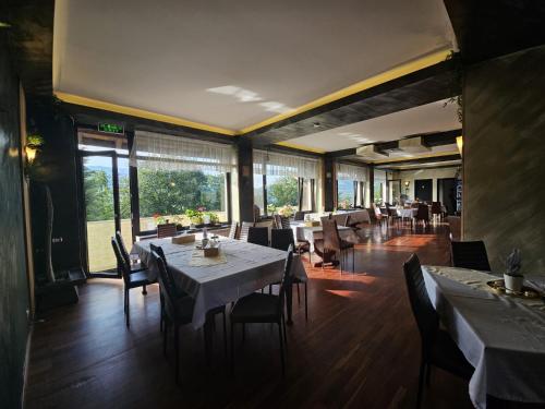 a dining room with tables and chairs and windows at Belvedere Resort Moieciu in Moieciu de Jos