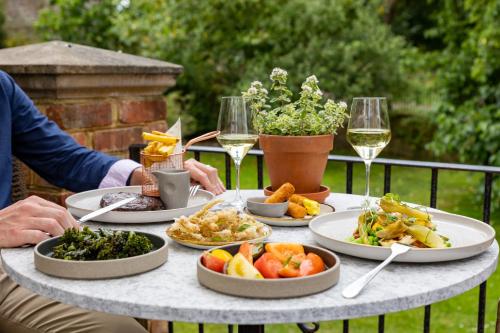 a table with plates of food and glasses of wine at Boys Hall in Willesborough