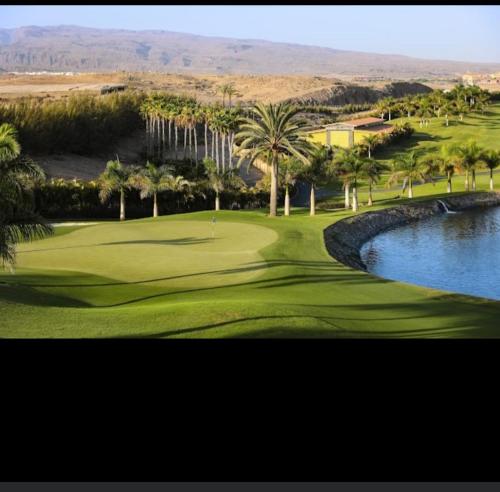 un campo de golf con palmeras y un estanque en La Casablanca, en Pasito Blanco