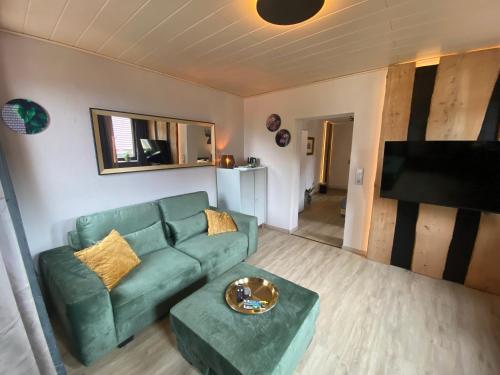 a living room with a green couch and a flat screen tv at Hotel & Restaurant Druidenstein in Trautenstein