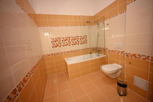 a bathroom with a toilet and a tub and a sink at Mercure Sighisoara Binderbubi Hotel & Spa in Sighişoara