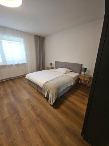 a bedroom with a large bed and a wooden floor at Apartmán VAJANA Exclusiv & Jacuzzi in Piešťany