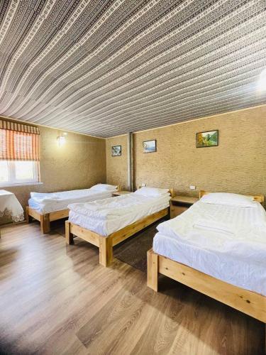 a room with three beds and a ceiling at Guest house Amirhan in Bokonbayevo