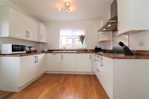 a white kitchen with white cabinets and a wooden floor at Signature - Morrison House in Glasgow