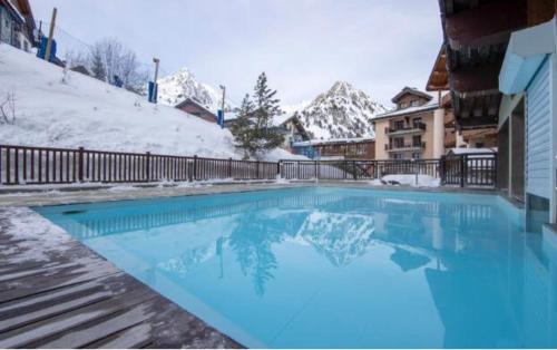 une grande piscine bleue dans la neige dans l'établissement Appartement 4-5 personnes skis aux pieds piscine intérieure sauna hammam, à Arc 1950