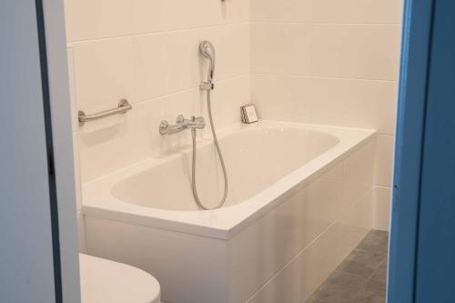 a white bath tub with a shower in a bathroom at Het Wapen van Elst in Elst