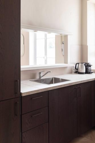 La cuisine est équipée de placards bruns et d'un évier. dans l'établissement Chic apartment - 5BR-10P - Grenelle-Eiffel Tower, à Paris