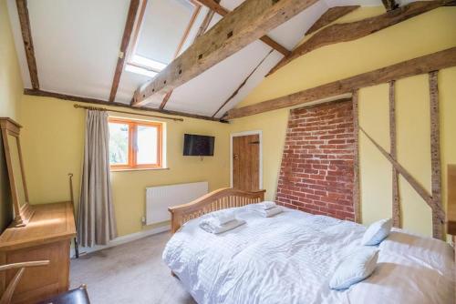 a bedroom with a bed and a brick wall at Little Swattesfield, Eye in Eye