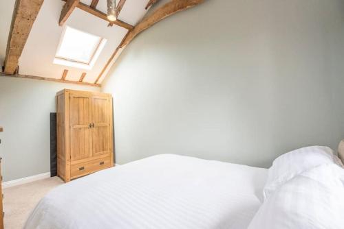 a bedroom with a white bed and a wooden cabinet at Little Swattesfield, Eye in Eye