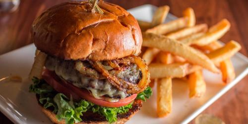 a white plate with a hamburger and french fries at Hotel Indigo Vancouver Dwtn - Portland Area by IHG in Vancouver