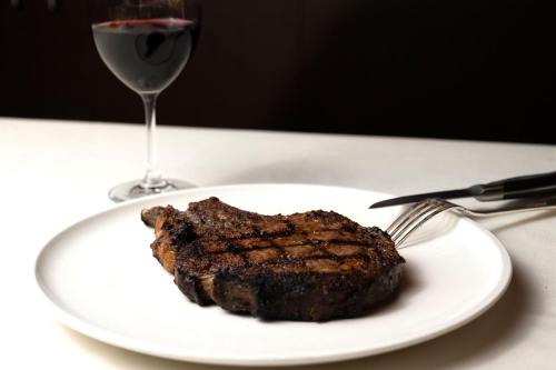 a piece of steak on a plate next to a glass of wine at Hotel Indigo Vancouver Dwtn - Portland Area by IHG in Vancouver