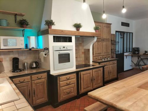 La cuisine est équipée de placards en bois et d'un four blanc. dans l'établissement Le Bois de Luché, à Rom