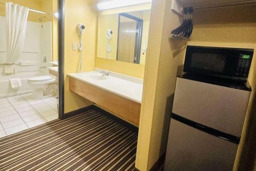 a bathroom with a sink and a toilet and a refrigerator at Super 8 by Wyndham Warrenton in Warrenton