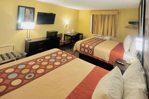 a hotel room with two beds and a television at Super 8 by Wyndham Warrenton in Warrenton