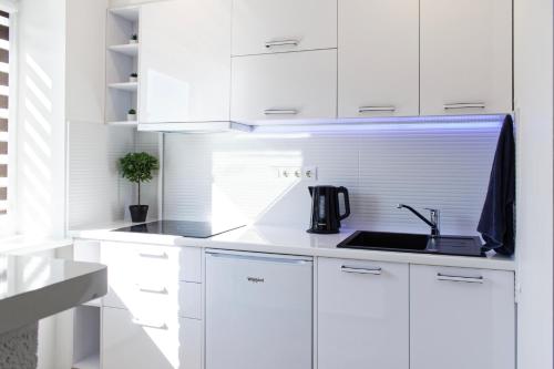 kuchnia z białymi szafkami i zlewem w obiekcie Studio apartment w mieście Valmiera