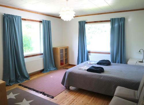 a bedroom with blue curtains and a bed with a chair at Villa Siikakoski in Konnevesi