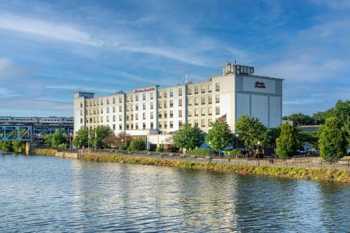 a large white building next to a body of water at Hampton Inn & Suites Newark-Harrison-Riverwalk in Newark