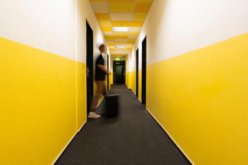 a man standing in a hallway with yellow walls at Industriepalast Berlin in Berlin