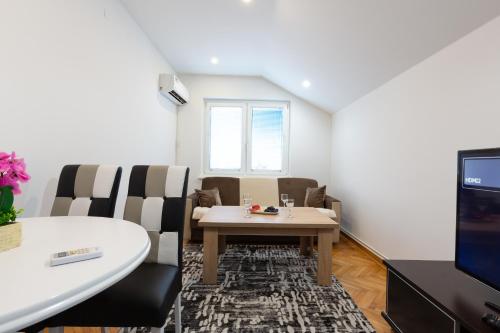 a living room with a table and chairs and a tv at Evergreen Apartments in Visoko