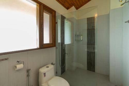 a bathroom with a toilet and a glass shower at StayVista at The Woods with Indoor Fireplace & BBQ in Chail