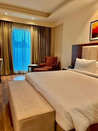 a hotel room with a large bed and a chair at Best Western Plus Amritsar in Amritsar
