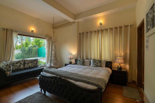 a bedroom with a bed and a couch and a window at StayVista at The Woods with Indoor Fireplace & BBQ in Chail