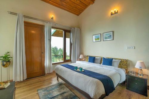 a bedroom with a large bed and a large window at StayVista at The Woods with Indoor Fireplace & BBQ in Chail