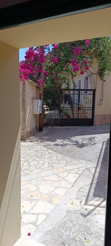 a gate with a tree with pink flowers on it at Traditional two level Apartment in Liapades