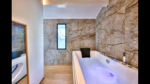 La salle de bains est pourvue d'une baignoire blanche et d'un mur en pierre. dans l'établissement Duplex centre historique Cannes, à Cannes
