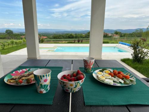 a table with plates of food and bowls of fruit at Hacienda R - kuca sa bazenom in Siokovac