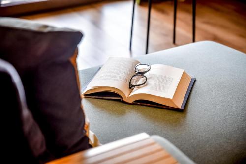 an open book with a pair of glasses sitting on a table at Podtatrzańskie Apartamenty in Nowy Targ