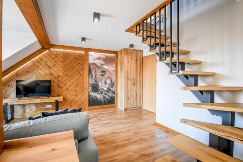 a living room with a staircase and a couch at Podtatrzańskie Apartamenty in Nowy Targ