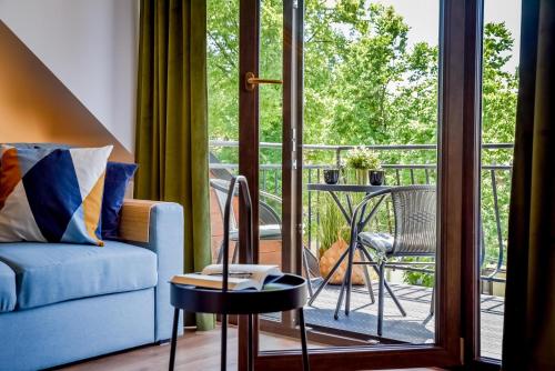 a living room with a blue couch and a balcony at Podtatrzańskie Apartamenty in Nowy Targ