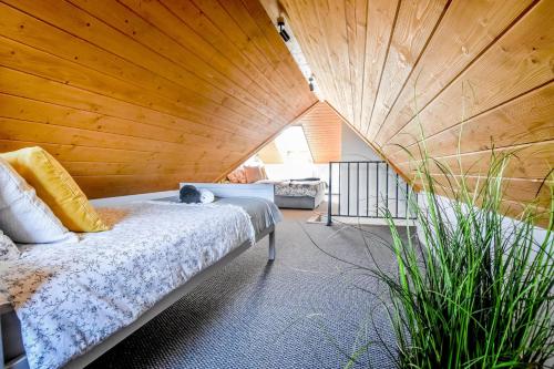 a room with a bed and a wooden ceiling at Podtatrzańskie Apartamenty in Nowy Targ