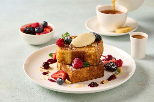 a plate of french toast with berries and a cup of coffee at Hilton Dubai Al Habtoor City in Dubai
