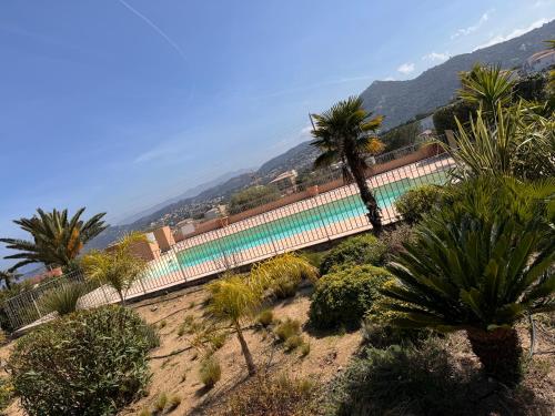un palmier et un bâtiment avec une clôture dans l'établissement Joli studio tout confort proche toutes commodités dans residence calme, à LʼÎle-Rousse