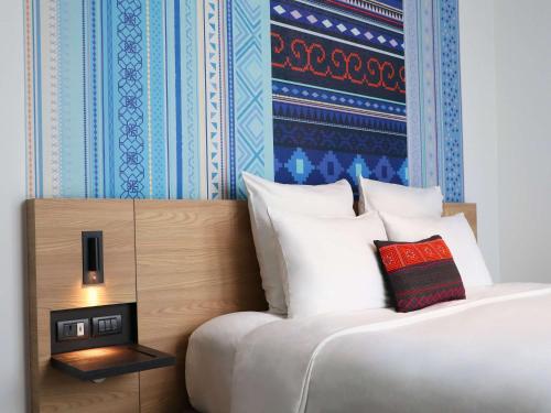 清迈Novotel Chiangmai Nimman Journeyhub的一张带白色枕头和蓝色墙壁的床