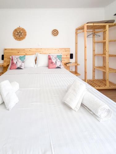 a bedroom with a bed with white sheets and pink pillows at Village View Apartments in Himare
