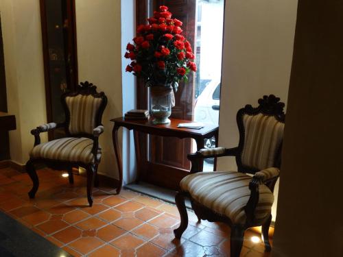 two chairs and a table with a vase of red flowers at Siena Hotel in Cuenca