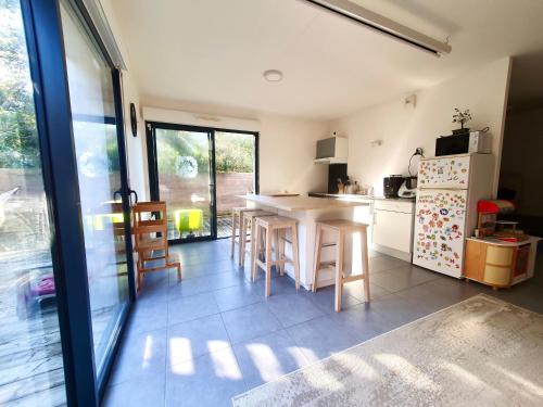 a kitchen with a table and chairs and a refrigerator at Maison de famille à 300m de la plage in Labenne