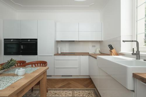 a kitchen with white cabinets and a wooden table at Vila Zlatý Slavík - Luxurious Villa with Spa in Jevany