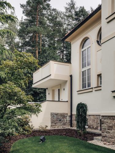 a white house with a window and a lawn at Vila Zlatý Slavík - Luxurious Villa with Spa in Jevany