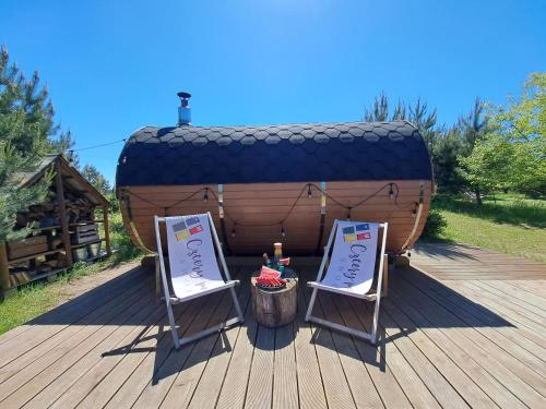 a wooden deck with two chairs and a barrel at 4 Pokoje Swory in Swornegacie 