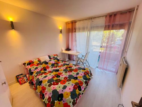 - une chambre avec un lit doté d'une couverture fleurie et d'une fenêtre dans l'établissement grand appartement 74m2 refait à neuf à 5mn de la mer dans grand parc botanique, à Villeneuve-Loubet
