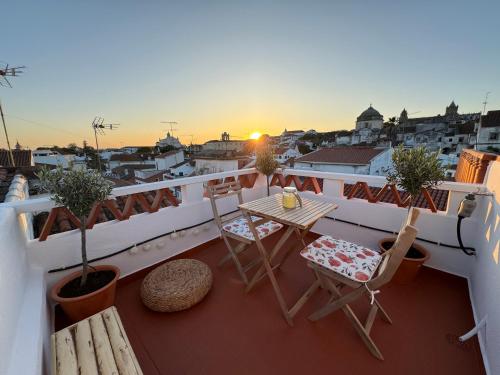 a balcony with a table and chairs and the sunset at Private Alentejo house with a terrace in Évora